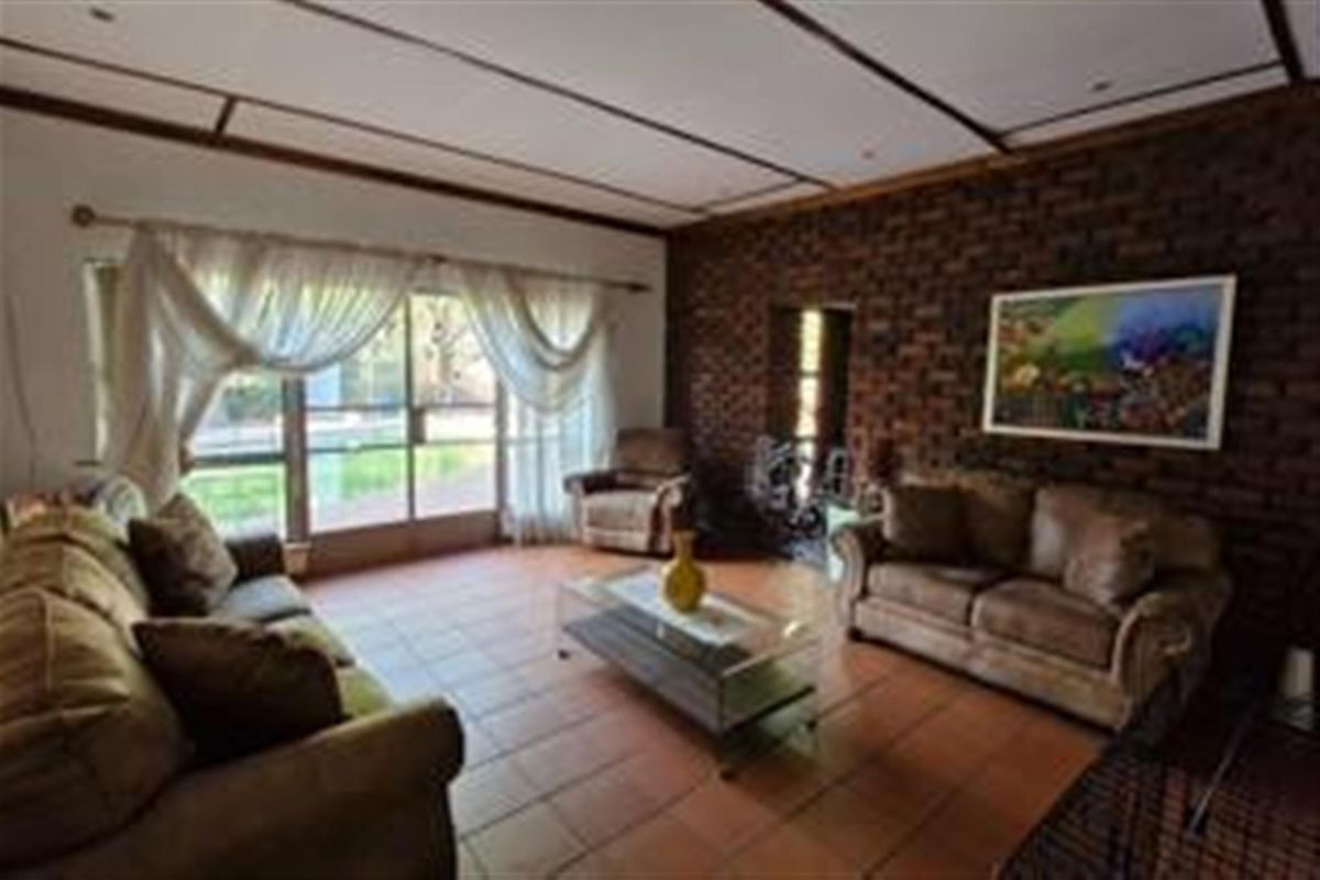 A living room featuring an exposed brick feature wall, tiled flooring, and large sliding glass doors providing access to the outdoor area.