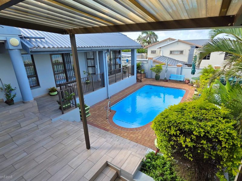 Outdoor pool area featuring a paved patio, swimming pool, and covered terrace, providing a functional space for outdoor relaxation and entertainment.
