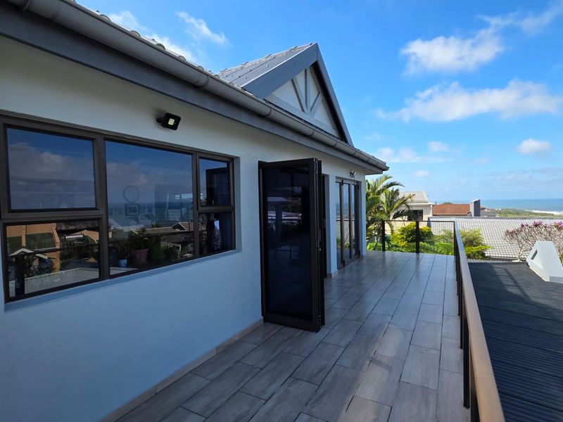 Spacious elevated balcony featuring modern wood-look tiled flooring, glass balustrades, and expansive views, providing a seamless transition between indoor and outdoor living spaces.