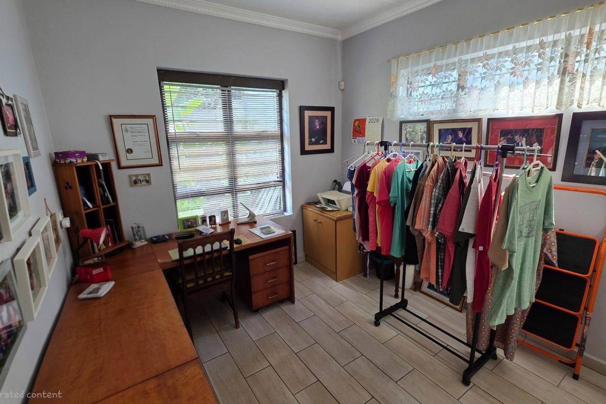 A functional bedroom or home office space featuring tiled flooring, built-in window blinds, and crown molding.