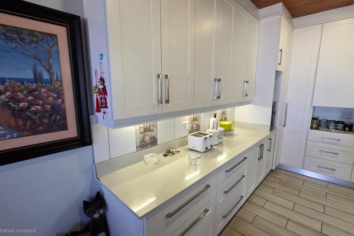 A modern kitchen featuring white cabinetry, stone countertops, tiled backsplash, and light-colored floor tiles, offering a clean and functional workspace.