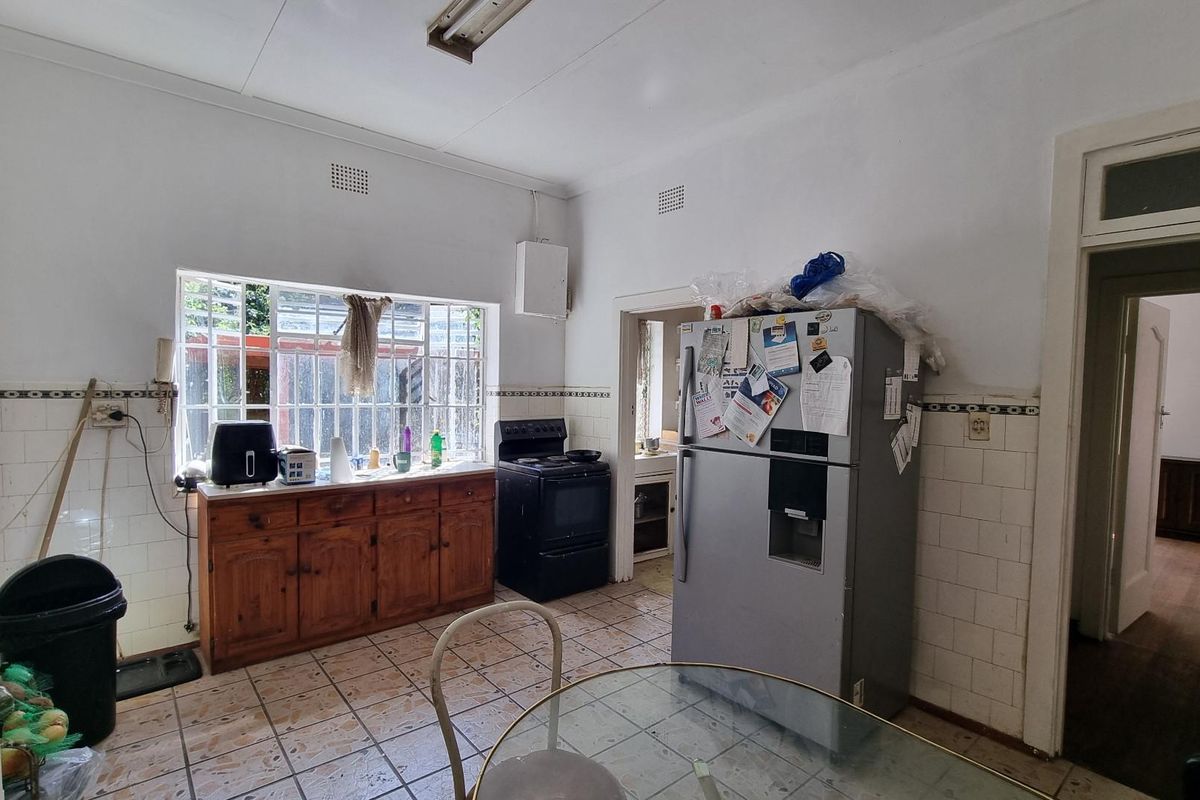 A dated kitchen featuring tiled flooring, ceramic wall tiles, and wooden cabinetry, offering potential for a modern renovation.