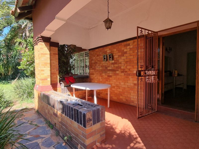 A covered outdoor patio featuring brick masonry walls and pillars with tiled flooring, providing a functional space for outdoor relaxation.
