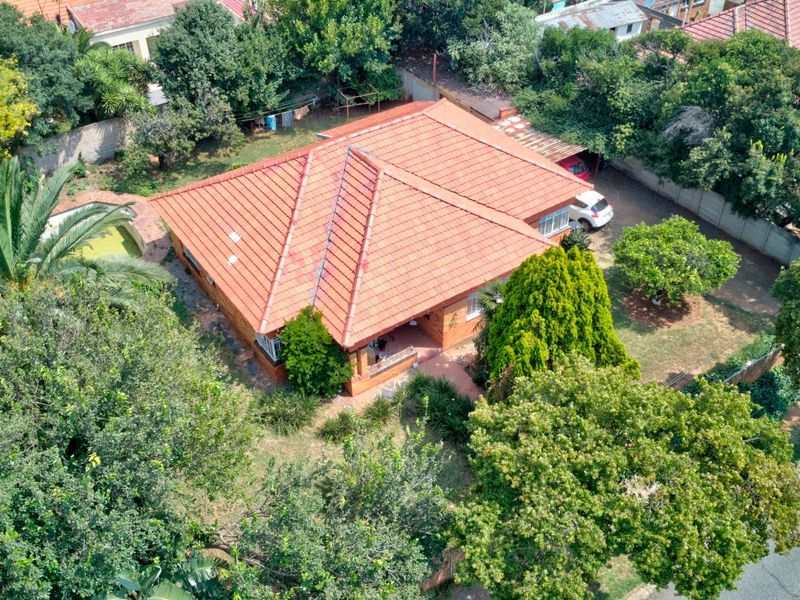 Aerial view of a residential property featuring a tiled roof, brick exterior, and established garden surroundings.