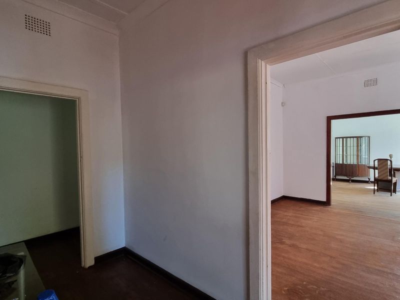 A neutral hallway featuring timber flooring and traditional architraves, providing access to adjacent living spaces.