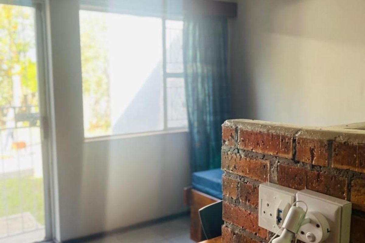 A functional living space featuring a brick partition wall with integrated electrical outlets, tiled flooring, and direct access to an outdoor area.