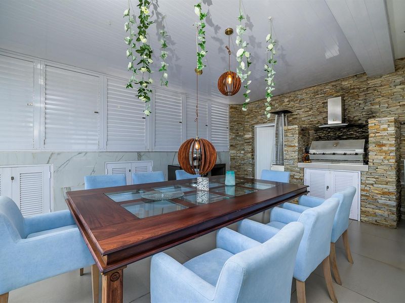 Covered patio area featuring a built-in braai, stone cladding feature wall, and tiled flooring, ideal for outdoor dining and entertainment.