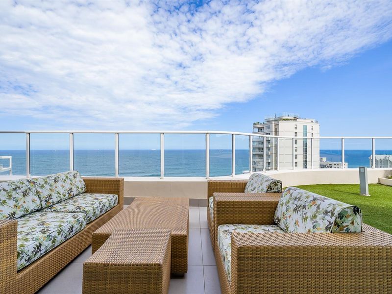Spacious balcony featuring tiled flooring, artificial grass section, and a glass balustrade, offering panoramic ocean views.