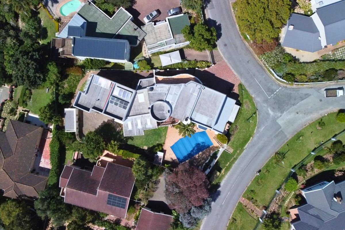 Aerial view of the property showing the roof structure, swimming pool, and surrounding garden area within the residential neighborhood.