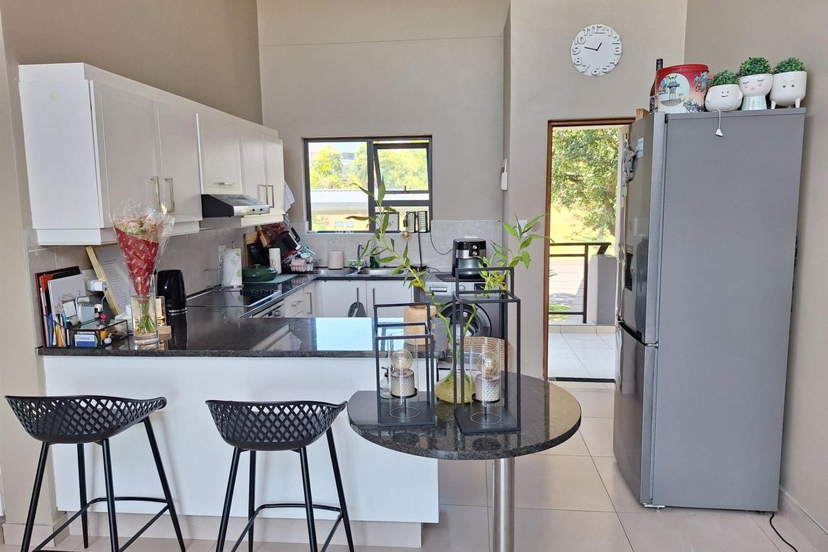 A functional kitchen featuring white cabinetry, granite countertops, a breakfast bar, and direct access to an outdoor balcony area.