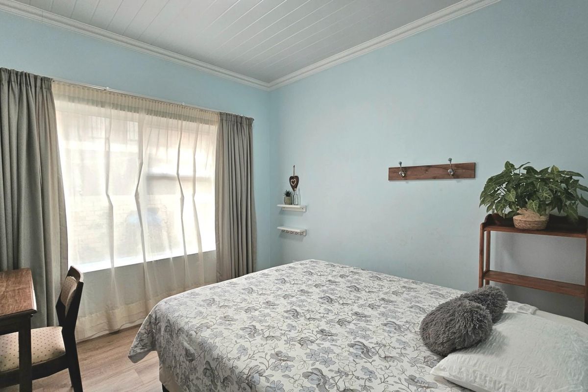 A bedroom featuring light blue walls, a white tongue-and-groove ceiling, and wood-look flooring, providing a simple and functional living space.
