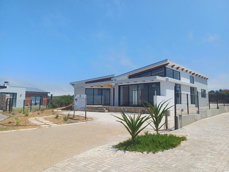 Modern single-story residence featuring a contemporary architectural design with large glass sliding doors, exposed timber rafters, and a paved driveway.