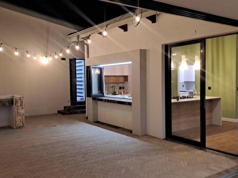 A covered patio area featuring a built-in serving counter and seamless transition to the modern kitchen through large sliding glass doors.