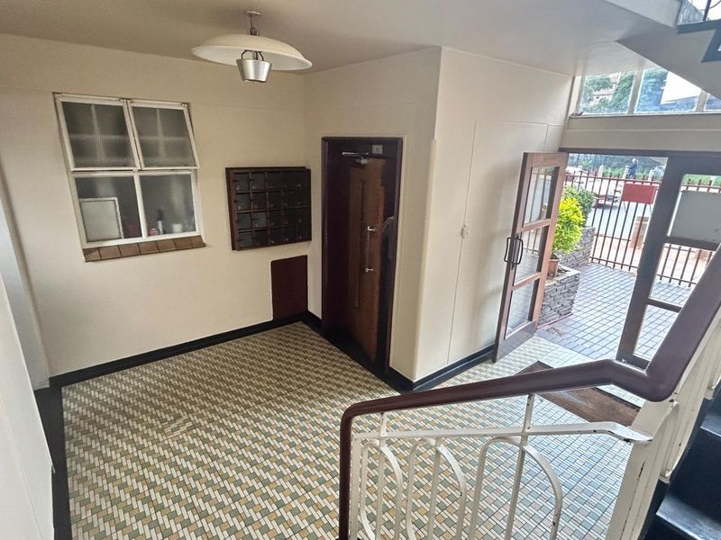 Commercial building entrance lobby featuring tiled flooring, a built-in mail collection unit, and access to an external paved area and staircase.