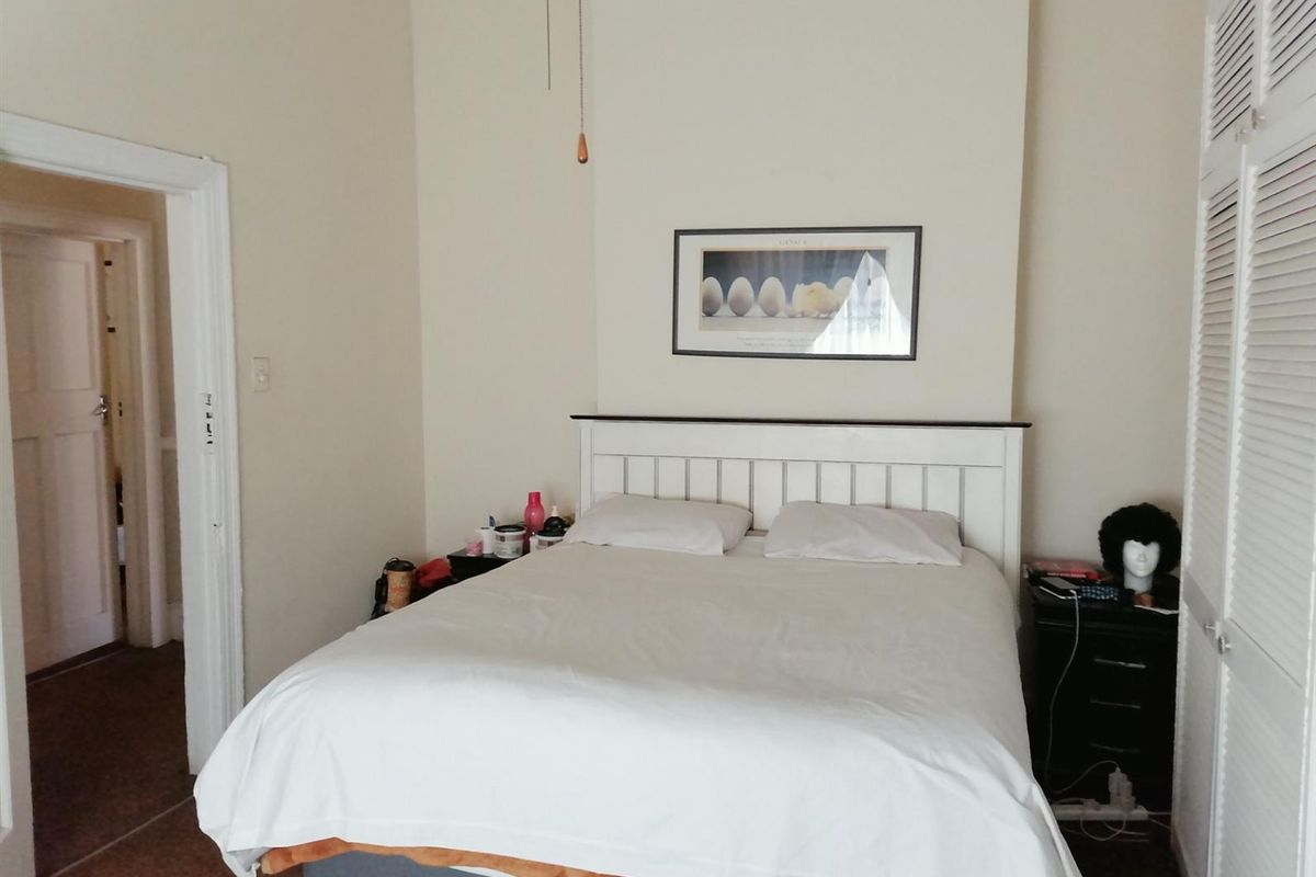 A bedroom featuring built-in louvered door cupboards and a central chimney breast, providing a functional and traditional layout.