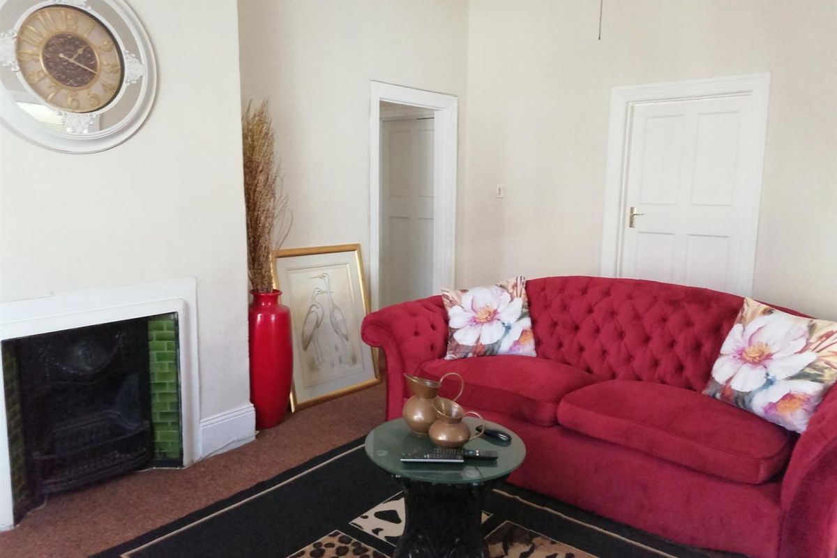A living room featuring a traditional fireplace with green tile surround and classic panelled interior doors.