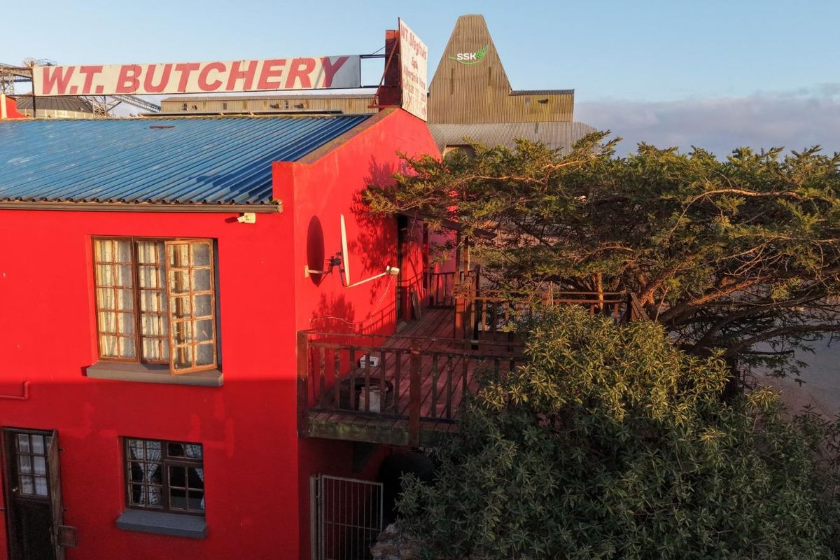 Aerial view of a commercial building featuring a prominent red facade, metal roof, and an elevated timber balcony area.