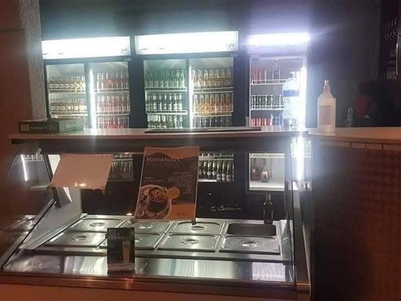 A commercial-style bar area featuring a refrigerated display counter and multiple built-in glass-front beverage coolers.