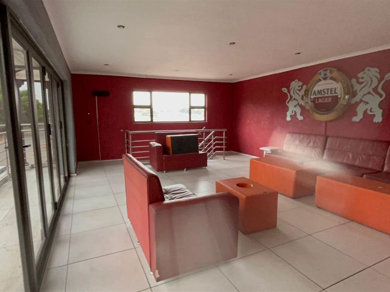 Spacious entertainment area featuring tiled flooring, large sliding glass doors leading to a balcony, and recessed ceiling lighting.