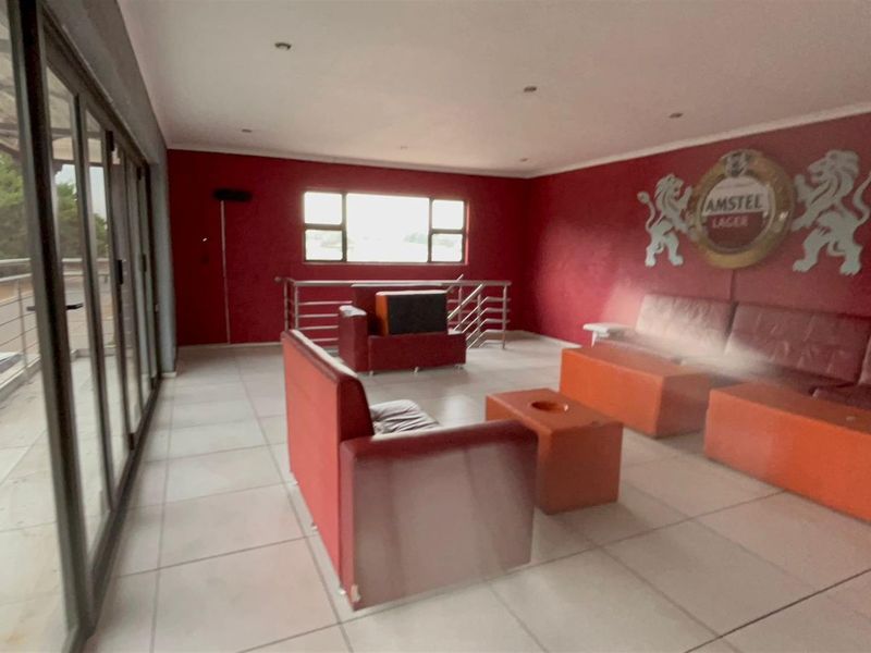 Spacious living area featuring large glass sliding doors, tiled flooring, and recessed ceiling lighting, offering a versatile space for relaxation or entertainment.