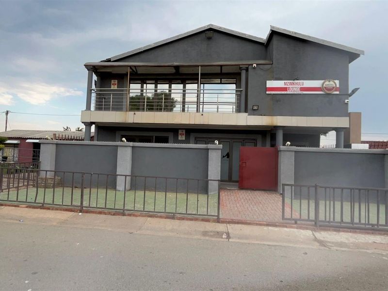 A two-story commercial or residential property featuring a balcony, perimeter wall, and gated entrance, currently utilized as a lounge.