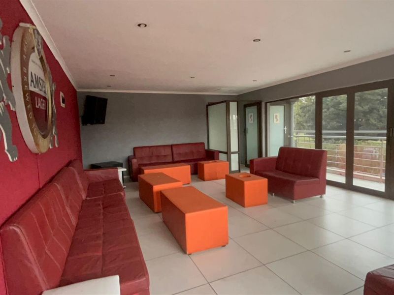 Spacious entertainment area featuring large format floor tiles, recessed ceiling lighting, and expansive glass sliding doors leading to an outdoor balcony.