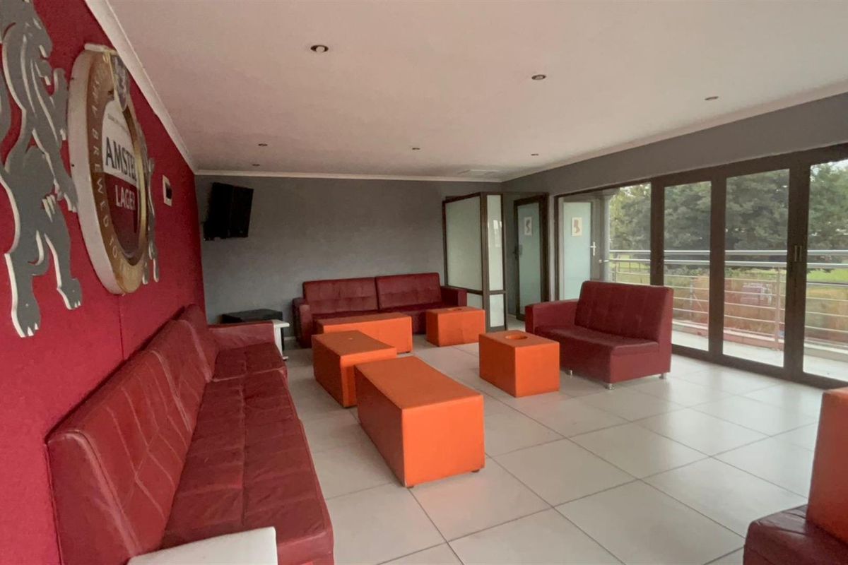 Spacious entertainment area featuring large format floor tiles, recessed ceiling lighting, and expansive glass sliding doors leading to an outdoor balcony.