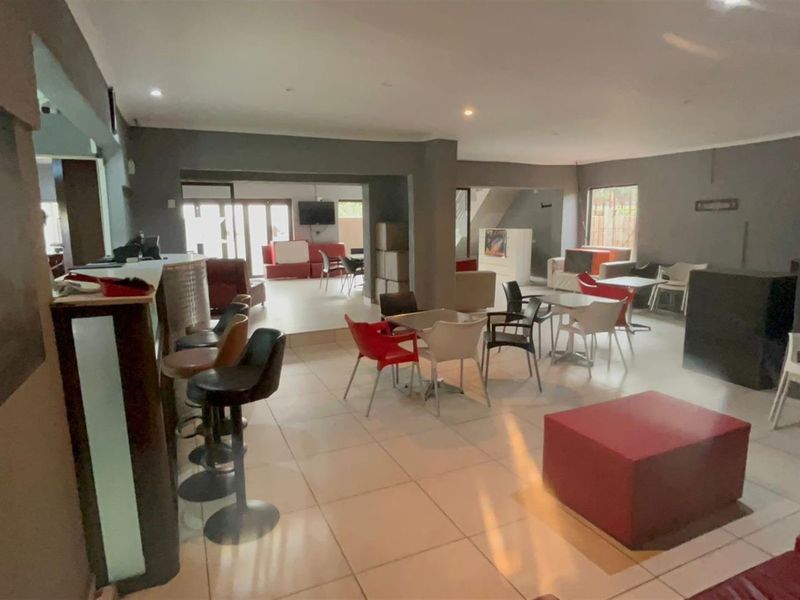 Spacious open-plan entertainment area featuring a built-in bar counter, tiled flooring, and neutral wall finishes, suitable for versatile living or social use.