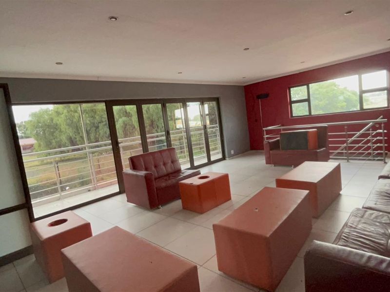Spacious open-plan living area featuring large sliding glass doors leading to a balcony, tiled flooring, and recessed ceiling lighting.