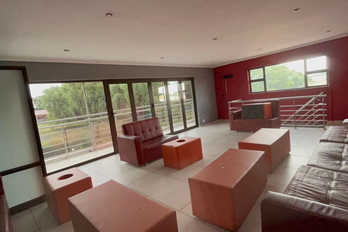 Spacious open-plan living area featuring large sliding glass doors leading to a balcony, tiled flooring, and recessed ceiling lighting.