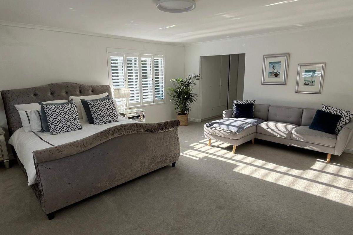 Spacious bedroom featuring neutral carpeting, built-in storage, and plantation shutters that allow for natural light.