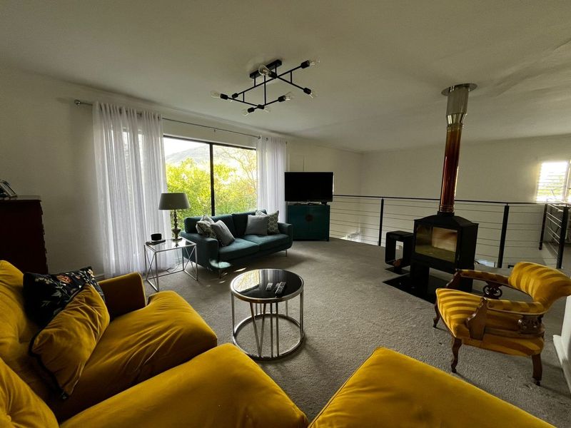 Spacious living room featuring a freestanding fireplace, modern lighting, and large sliding doors that provide natural light and views.
