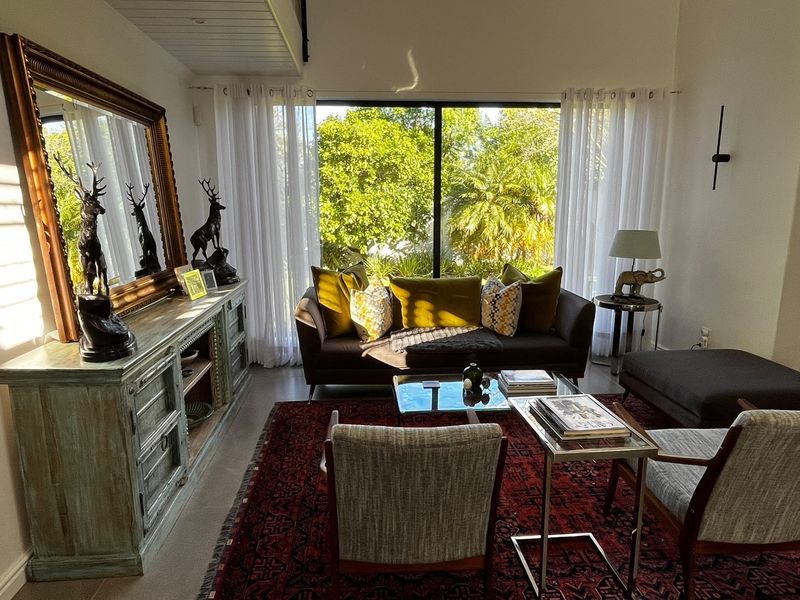 A bright and inviting living room featuring large sliding glass doors that provide ample natural light and a view of the lush garden.