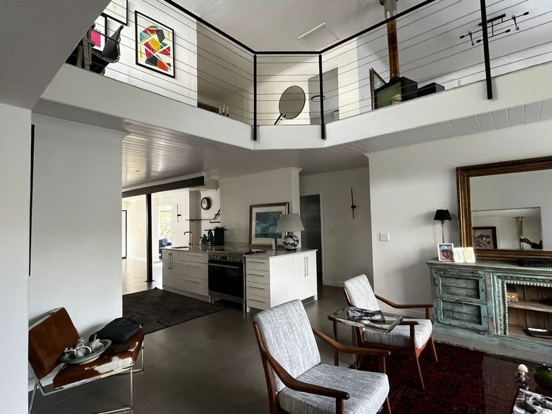 Spacious open-plan living area featuring a modern kitchen island, mezzanine level with metal balustrade, and a wood-burning fireplace.