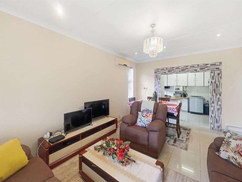 Open plan living area featuring tiled flooring, recessed lighting, and a decorative tiled archway leading into the kitchen space.