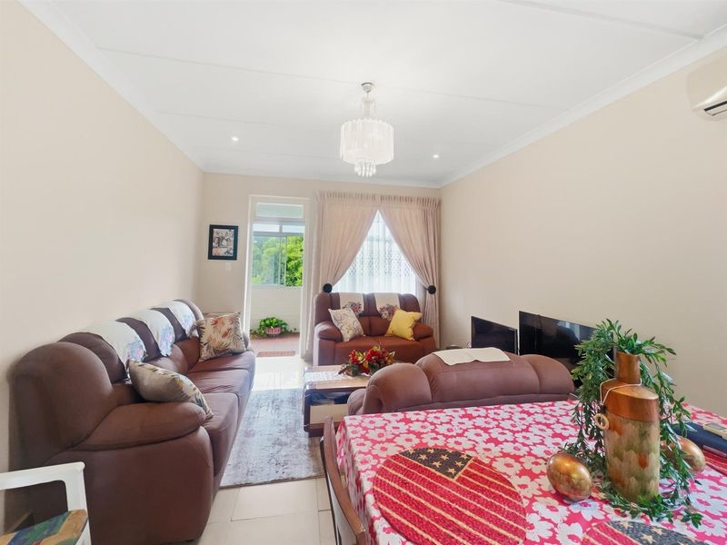 A bright open-plan living area featuring tiled flooring, crown molding, and direct access to an outdoor balcony space.