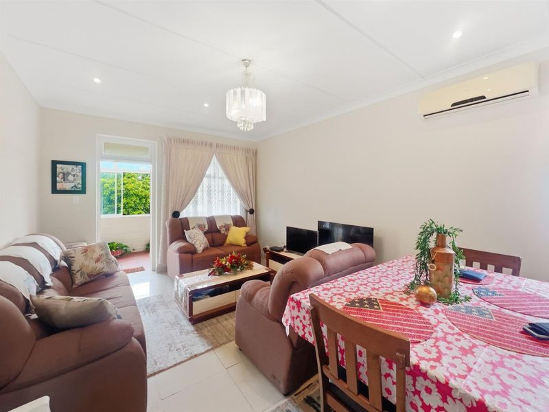 Open-plan living and dining area featuring tiled flooring, recessed lighting, a wall-mounted air conditioning unit, and direct access to a private balcony.