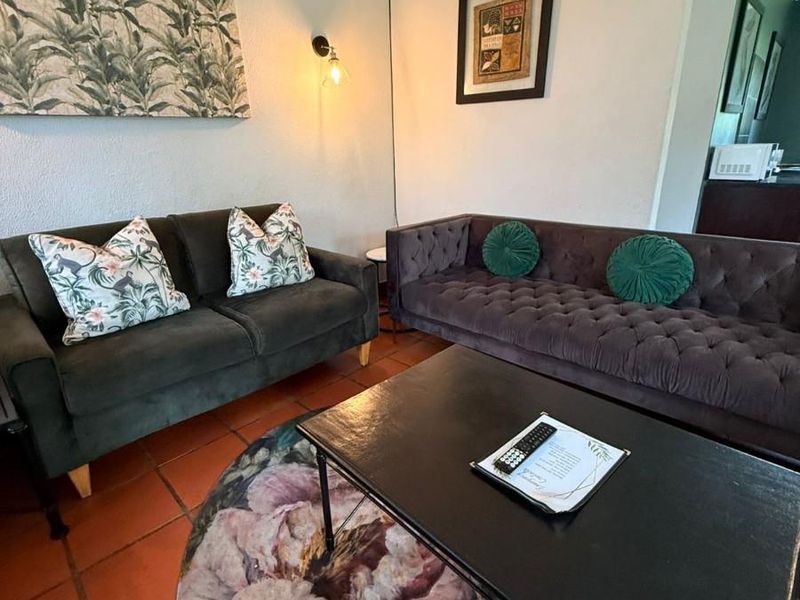 A cozy living room featuring terracotta floor tiles and wall-mounted lighting fixtures.