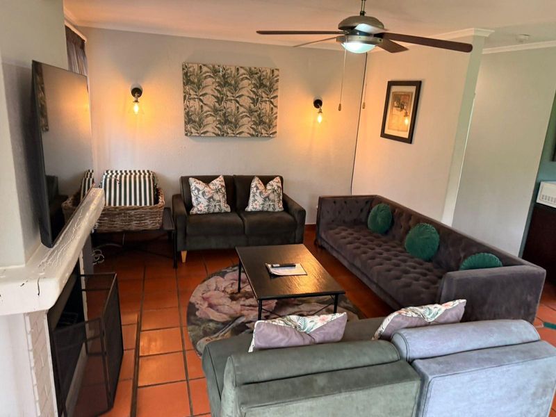 Cozy living room featuring a built-in fireplace, terracotta floor tiles, and a ceiling fan, creating a warm and inviting atmosphere.