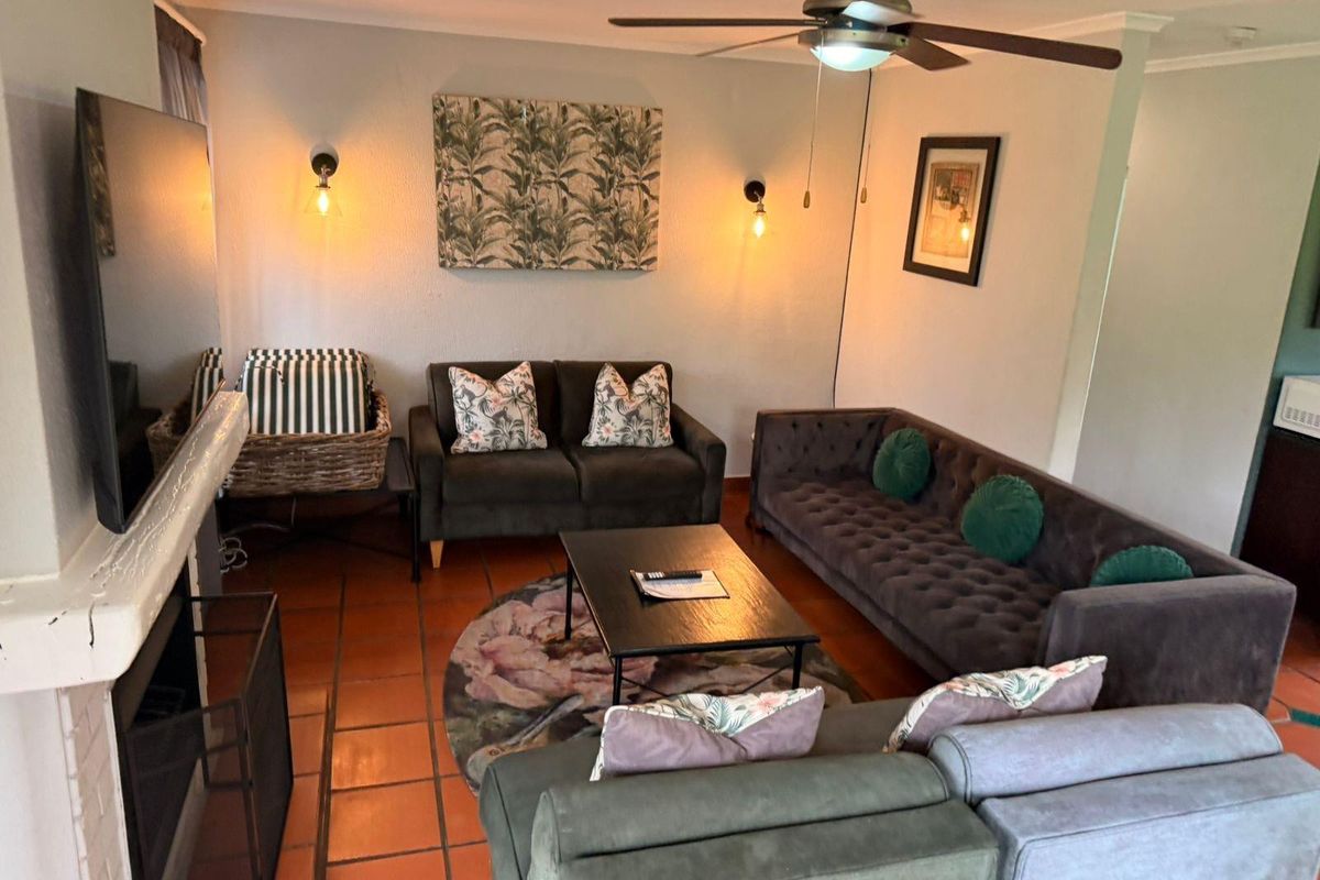 Cozy living room featuring a built-in fireplace, terracotta floor tiles, and a ceiling fan, creating a warm and inviting atmosphere.