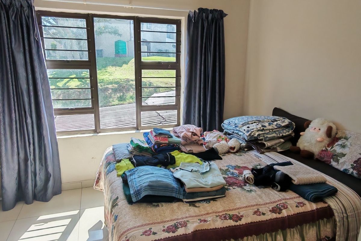 A bedroom featuring tiled flooring and large aluminium-framed windows that provide natural light.