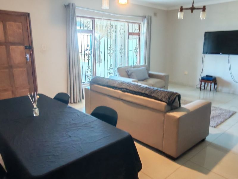 Spacious open-plan living and dining area featuring tiled flooring, large sliding glass doors with security gates, and neutral wall finishes.