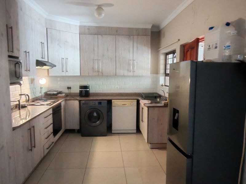 A functional kitchen featuring light wood-look cabinetry, subway tile backsplash, integrated oven, and tiled flooring, offering a practical layout for daily meal preparation.