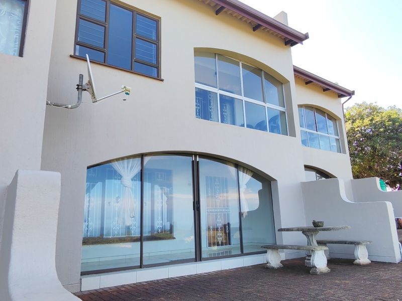 Rear elevation of the townhouse featuring arched glass doors, large windows, and a paved patio area overlooking the garden.