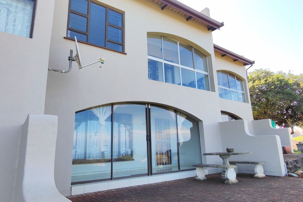 Rear elevation of the townhouse featuring arched glass doors, large windows, and a paved patio area overlooking the garden.