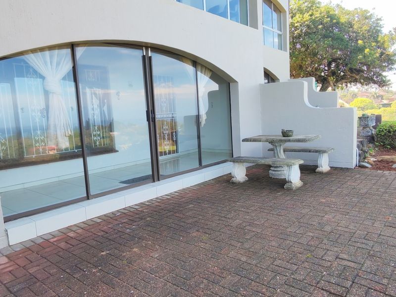 A paved outdoor patio area featuring arched sliding glass doors and a garden view, providing a functional space for outdoor relaxation.