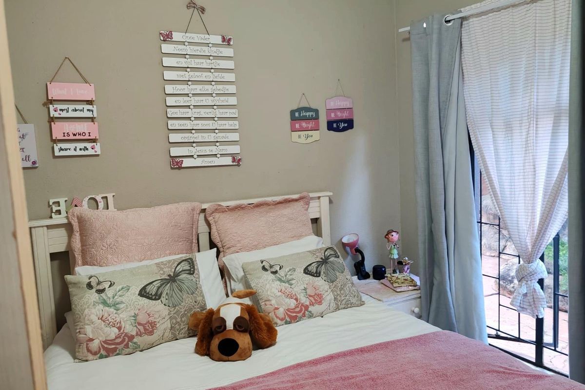 A cozy bedroom featuring neutral wall tones, a built-in bed frame, and direct access to an outdoor area through a secured glass door.