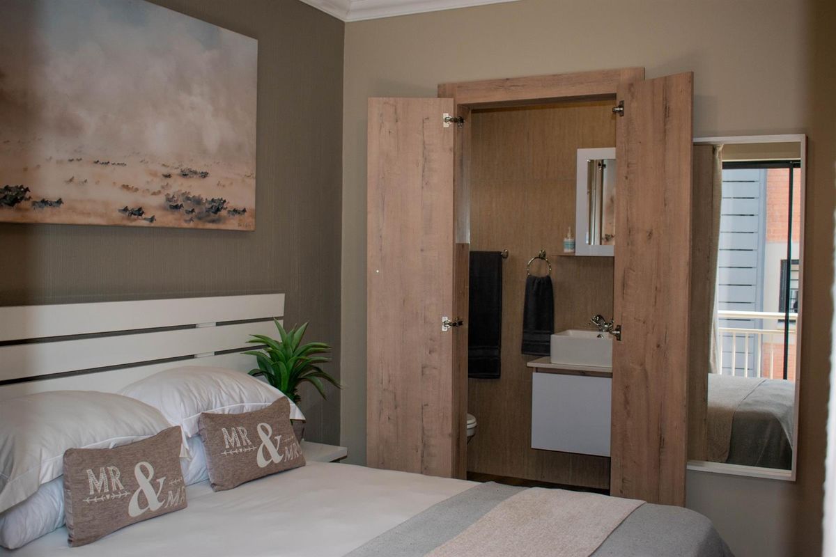 Bedroom featuring an integrated en-suite bathroom with a modern vanity and wood-look cabinetry, accessible through folding doors.