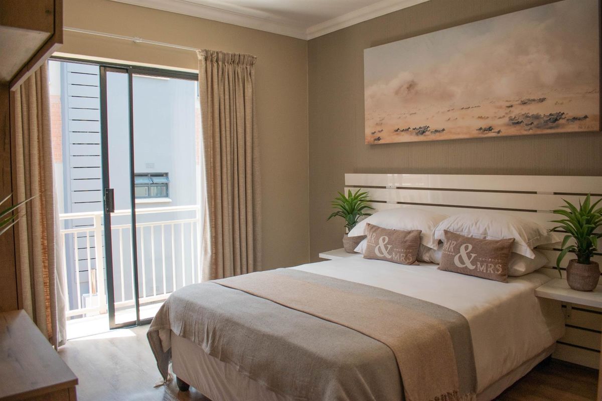 A well-maintained bedroom featuring a built-in headboard and sliding glass door access to a private balcony.