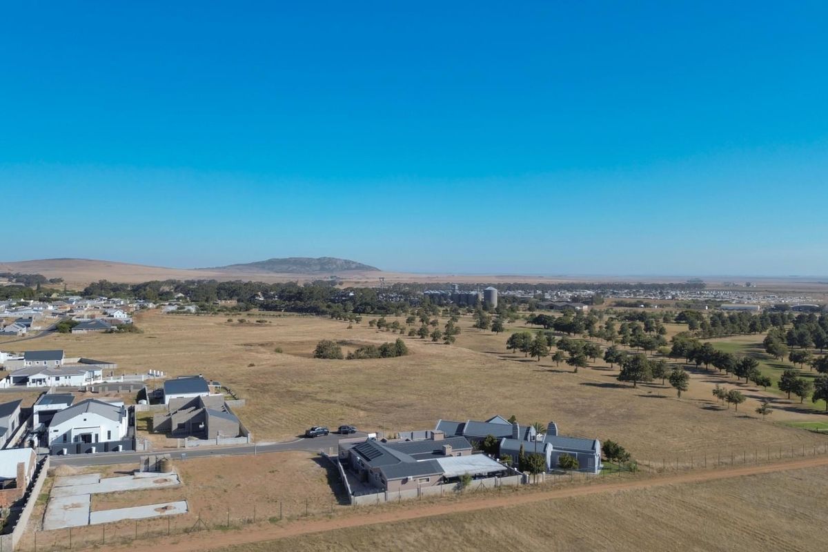 Aerial view of a residential estate featuring modern homes, surrounding open fields, and distant landscape views.